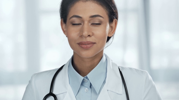mosolygó afroamerikai orvos fehér kabát sztetoszkóp nézett kamera - Felvétel, videó