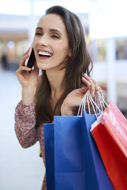Радость с полным мешков с покупками говорить по мобильному телефону
  - Фото, изображение
