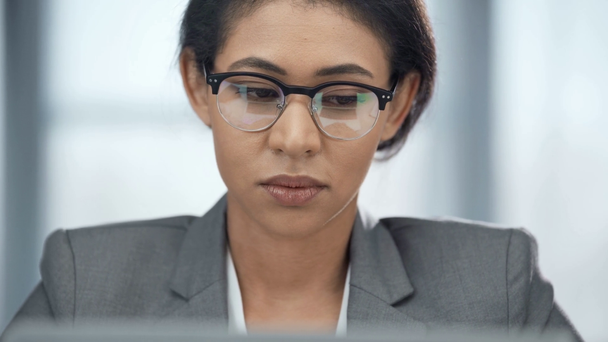 focused african american businesswoman in glasses looking away - Materiał filmowy, wideo