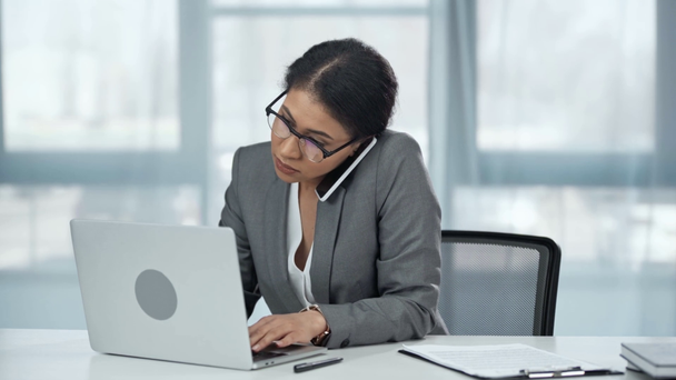 mujer de negocios afroamericana en gafas de escribir en el ordenador portátil y luego hablar en el teléfono inteligente
 - Imágenes, Vídeo