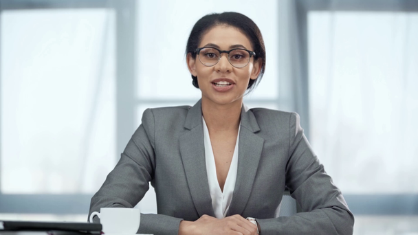 sonriente afroamericana mujer de negocios en gafas hablando en cámara
 - Imágenes, Vídeo