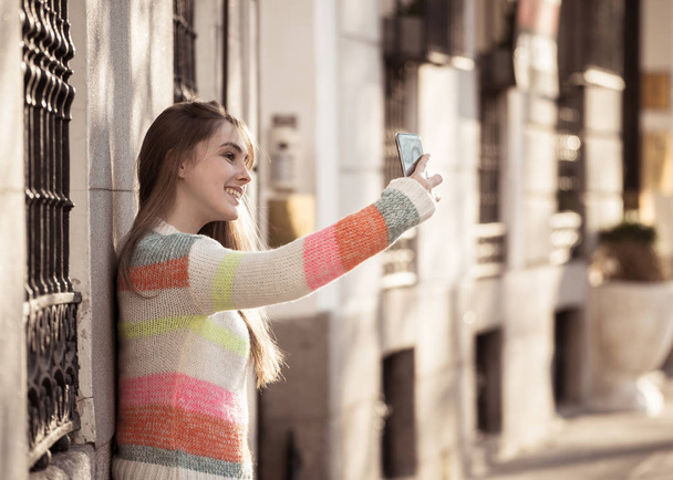 Pretty teenager girl taking selfie happy and excited in the city. Young student woman recording video of herself blogging outdoors In Millennial generation Connections Technology and Online trends. - Foto, imagen