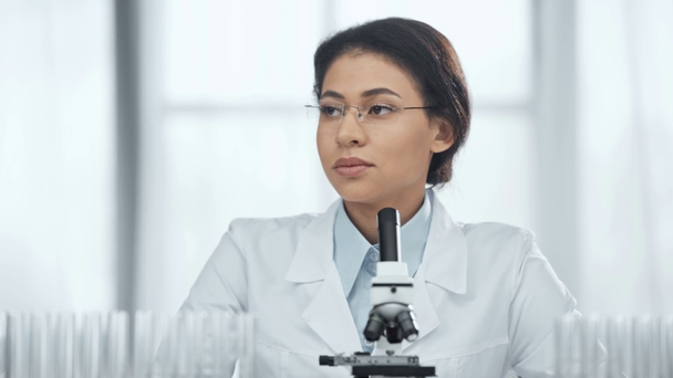 selektivní zaměření afrického amerického vědce na brýle s pohledem na krevní vzorky ve zkumavce v laboratoři  - Záběry, video