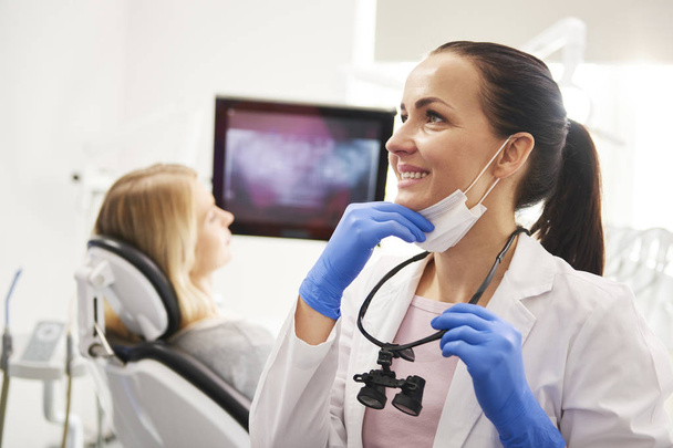 Ικανοποιημένος οδοντίατρος με οδοντιατρικό εξοπλισμό κάνει τη δουλειά της στην κλινική - Φωτογραφία, εικόνα