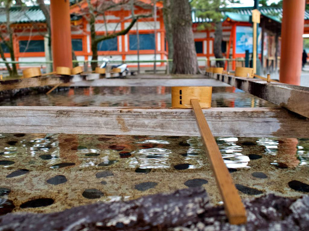 Japanse traditionele bamboe pollepel en de wasbak aan de voorkant van de Heian-tempel, Kyoto, Japan. Bamboe of houten pollepel en bekken zijn meestal te vinden aan de voorkant van het heiligdom in Japan - Foto, afbeelding