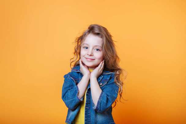 Studio portrait of smiling little girl on a yellow background - Foto, Imagen
