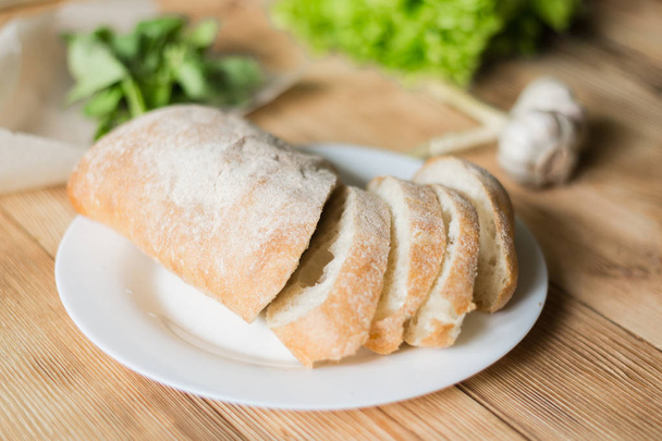 Sliced bread, ciabatta on a white plate. Preparation for the preparation of bruschetta. - Photo, image