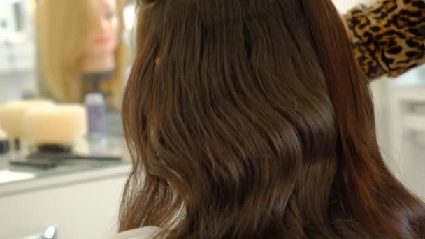 Egy nő fodrász csinál egy terjedelmes frizura, hogy az ügyfél segítségével a haj ironer, préseléséhez haj. Professzionális fodrász a munkahelyen. Master hogy frizura egy lány a szépségszalonban lassított - Felvétel, videó