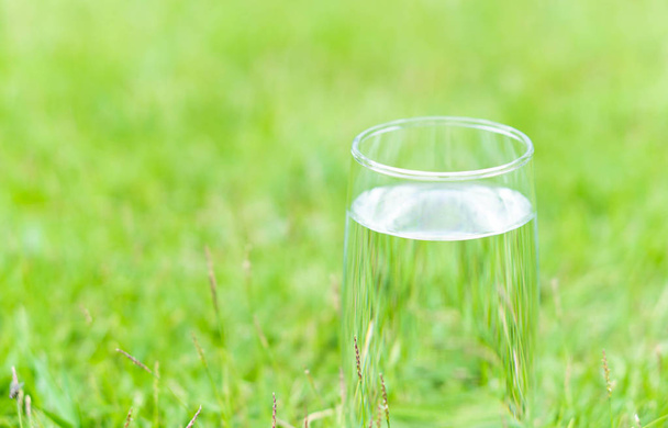 Closeup glass of water on green grass nature background, food healthy concept - Photo, Image