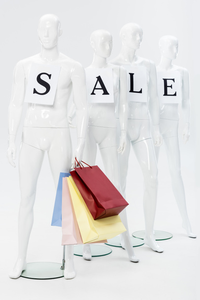mannequins with sale lettering on papers and shopping bags on grey - Фото, изображение