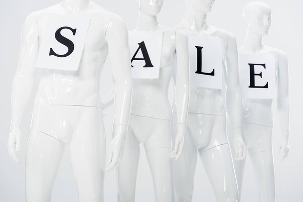 papers with sale lettering on white plastic mannequins on grey - Фото, изображение