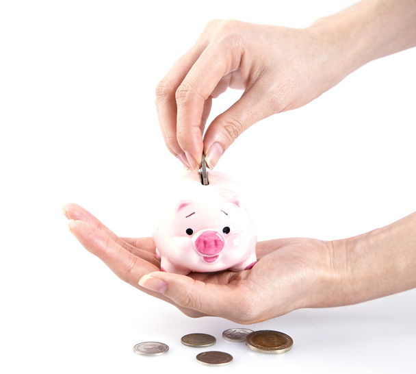 hand geld steken in een piggy bank - Foto, afbeelding