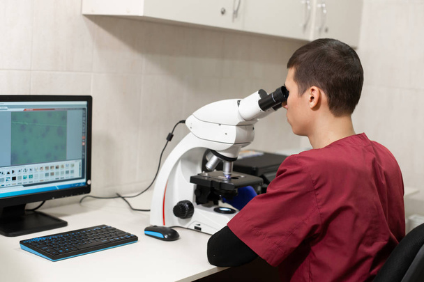 Mladý vědec, hledá prostřednictvím mikroskopem v laboratoři. Jo - Fotografie, Obrázek