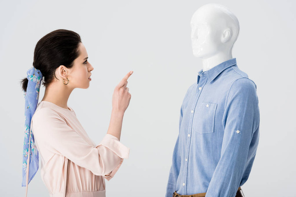 dissatisfied girl arguing and pointing with finger at mannequin isolated on grey - Fotografie, Obrázek
