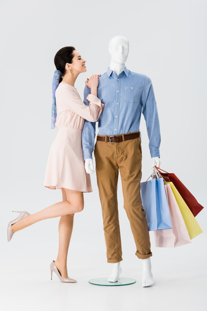 beautiful girl leaning on mannequin with shopping bags on grey - Foto, Bild