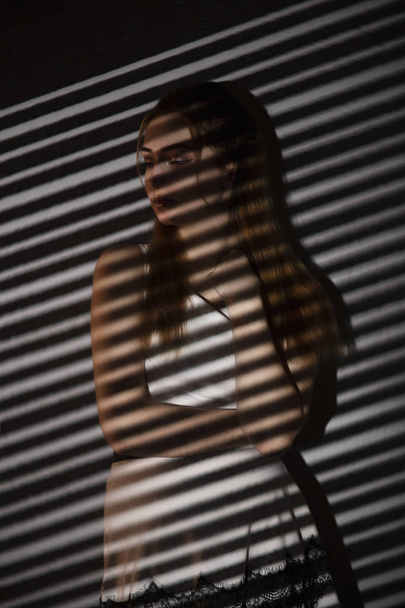 woman with light pattern of blinds, concept women's emotions and beauty, gobo masks - Foto, afbeelding