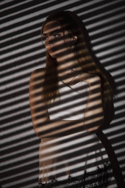 woman with light pattern of blinds, concept women's emotions and beauty, gobo masks - Foto, immagini
