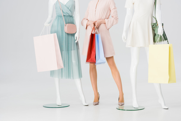 cropped view of young woman with shopping bags near mannequins on grey - Foto, imagen