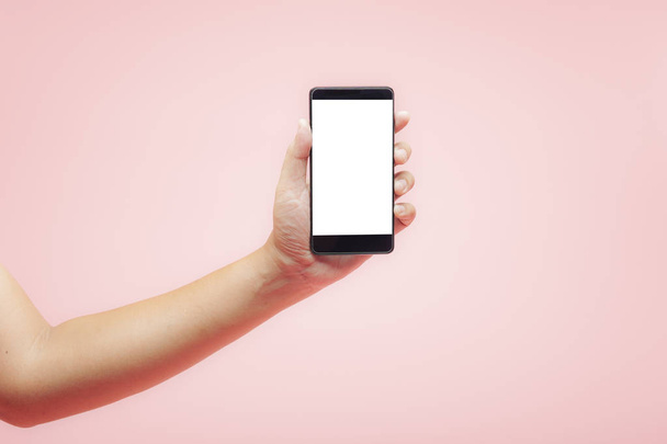 Kézben tartja smartphone fehér üres képernyő rózsaszín háttérb - Fotó, kép