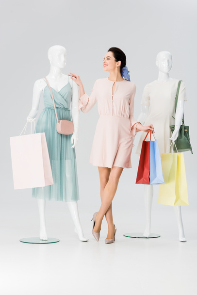 beautiful girl with shopping bags near mannequins on grey - Фото, зображення