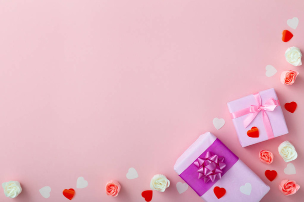 gifts with confetti hearts and roses, boxes wrapped in decorative paper on pastel colored pink background, top view, holiday concept - Φωτογραφία, εικόνα