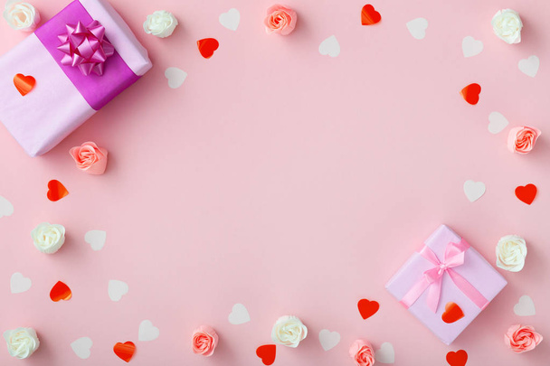 gifts with confetti hearts and roses, boxes wrapped in decorative paper on pastel colored pink background, top view, holiday concept - Fotoğraf, Görsel
