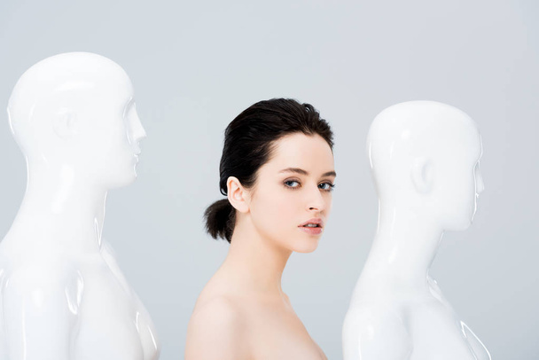beautiful girl near white mannequins looking at camera isolated on grey - Fotoğraf, Görsel
