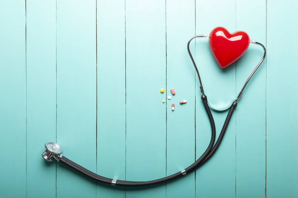 vista op di stetoscopi, modello di cuore rosso e farmaci su legno verde
 - Foto, immagini