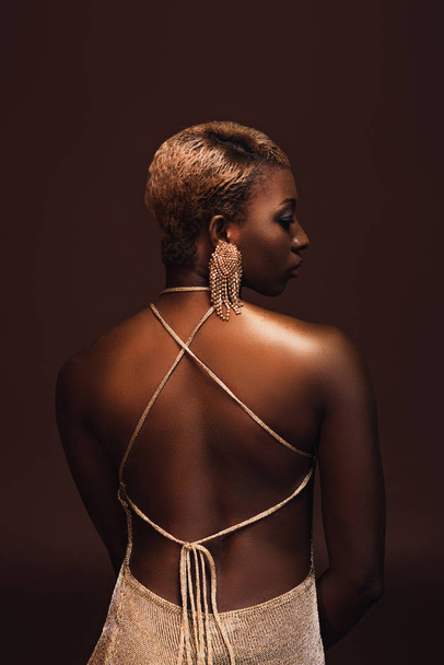 вид ззаду приваблива афроамериканська жінка з коротким волоссям ізольована на коричневому
 - Фото, зображення