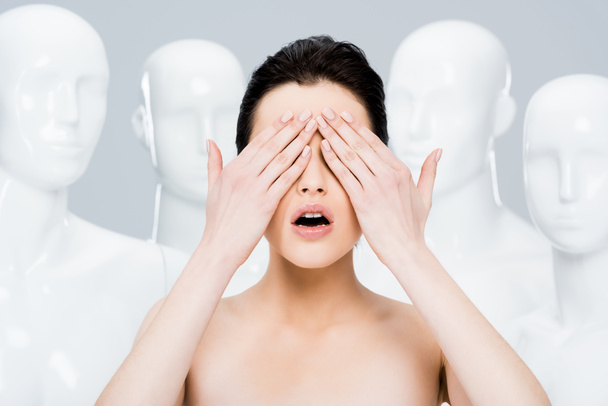 girl covering eyes while posing near mannequins isolated on grey  - Foto, Bild