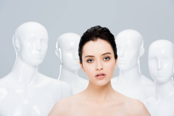 beautiful nude young woman looking at camera near mannequins isolated on grey  - Foto, Imagem