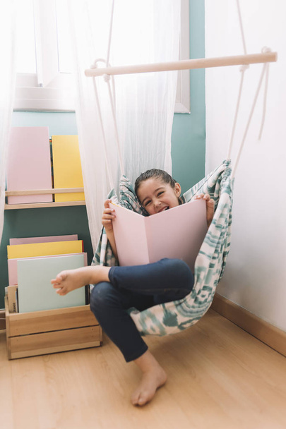 little girl laughs reading in her room - 写真・画像
