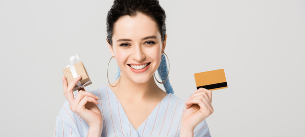 plan panoramique de belle fille élégante tenant boîte cadeau et carte de crédit isolé sur gris
 - Photo, image