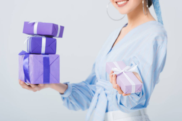 partial view of stylish girl holding gift boxes isolated on grey - Fotoğraf, Görsel