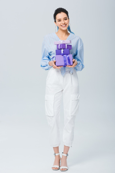 beautiful stylish girl holding gift boxes and smiling on grey - Foto, afbeelding