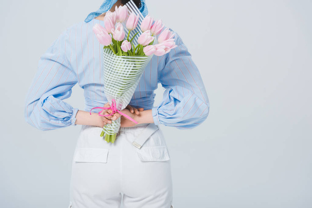 Achteraanzicht van stijlvol meisje met boeket van tulpen geïsoleerd op grijs met Kopieer ruimte - Foto, afbeelding
