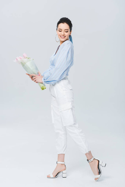beautiful stylish girl with bouquet of tulips smiling on grey - Foto, afbeelding