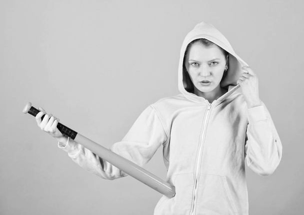 Feeling power. Woman play baseball game or going to beat someone. Girl hooded jacket hold baseball bat blue background. Woman in baseball sport. Baseball female player concept. She is dangerous - Foto, afbeelding