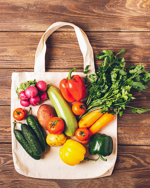 Cotton bag and fresh rustic vegetables on wooden background. Eco Concept. Copy space. Flat lay. - 写真・画像