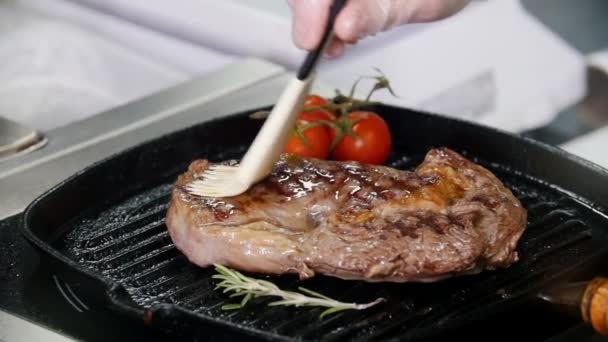 Working in the kitchen. Chef frying piece of steak in the pan. Rubs juice with a brush - Footage, Video