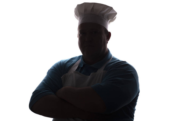 silhouette portrait of a good-natured man in cooker clothes , chef fold hands on his chest on white isolated background - Valokuva, kuva