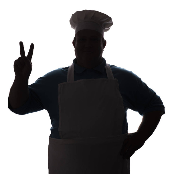 silhouette of man in cooker clothes, chef shows a greeting gesture with fingers on white isolated background, concept profession - Zdjęcie, obraz