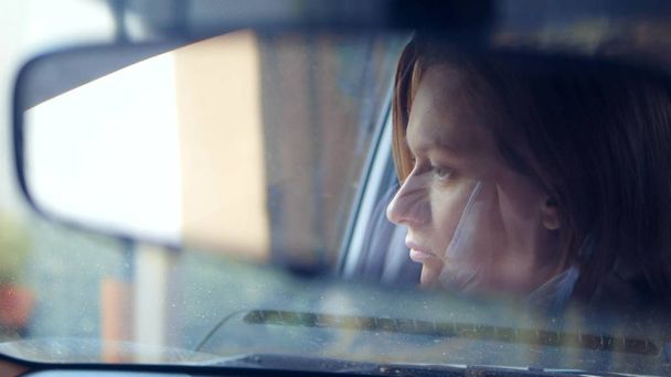 Reflection of a womans face in the rearview mirror, a woman prepares a rear-view mirror before driving - Фото, зображення