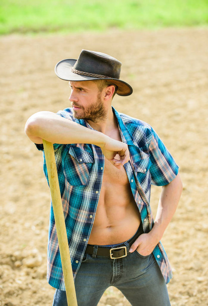 sexy farmer hold shovel. muscular ranch man in cowboy hat. farming and agriculture cultivation. Garden equipment. Eco farm. Harvest. happy earth day. Eco living. he loves her job - Fotó, kép