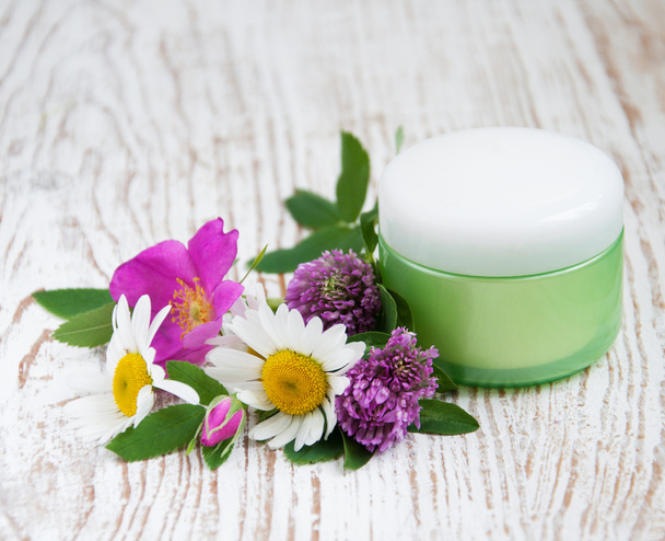 container with cream and wild flowers - Foto, Imagem