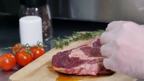 Restaurant kitchen. Chef preparing the meat. Pouring an oil on it - Imágenes, Vídeo