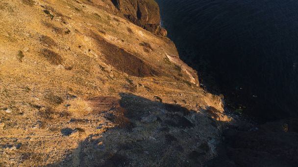 Aerial view of rocky calm ocean coast at the sunset. Shot. Beautiful view from the cliff edge on the ocean surface. - Photo, Image