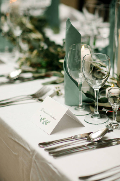 Elegant table setting at the restaurant. Wedding banquet with floral decoration on table, cards, glasses and cutlery closeup - Photo, Image