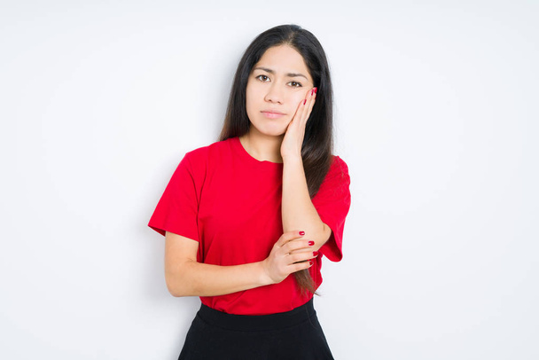 Beautiful brunette woman wearing red t-shirt over isolated background thinking looking tired and bored with depression problems with crossed arms. - Photo, Image