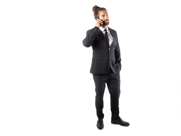 красивий молодий бізнесмен в чорному костюмі розмовляє по телефону ізольовано на білому
 - Фото, зображення